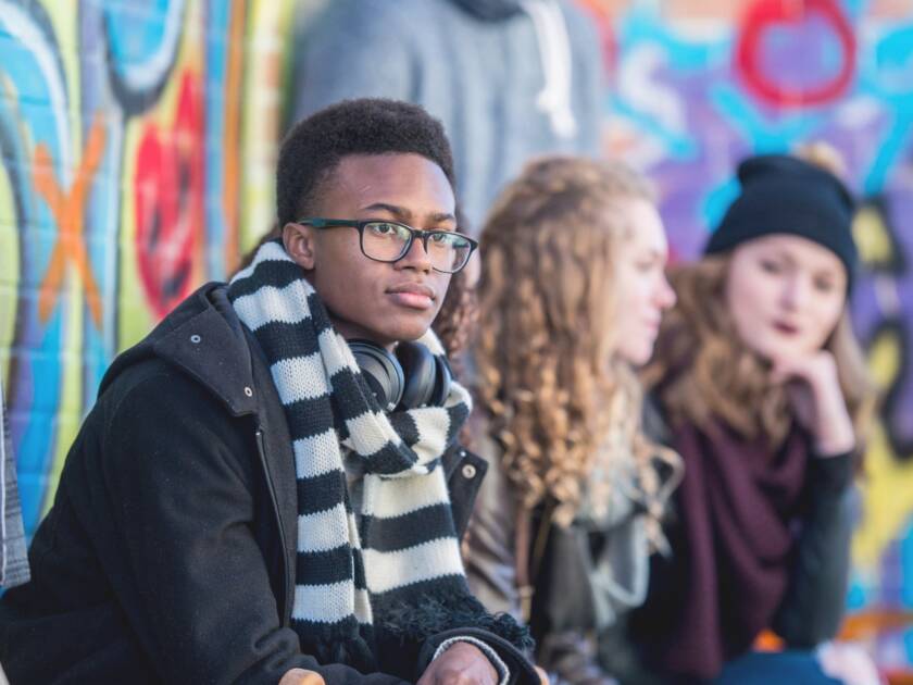 Young people are sitting in front of a graffiti wall.