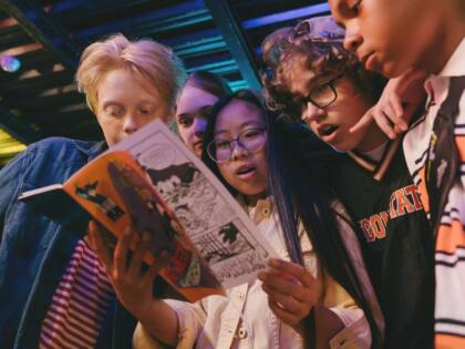 Several young people are looking at a magazine.