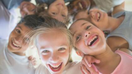 Young children looking into the camera and laughing.
