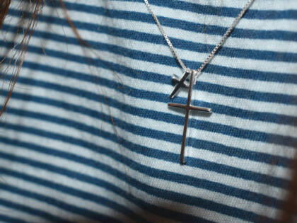 Two silver crosses around a persons neck.