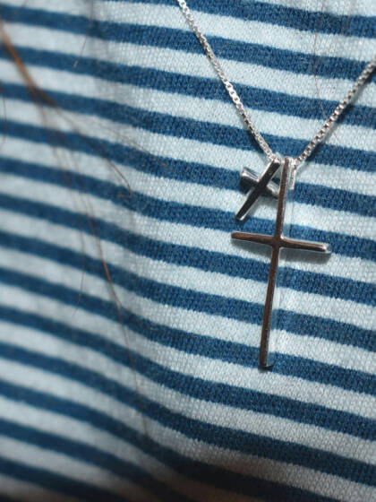 Two silver crosses around a persons neck.