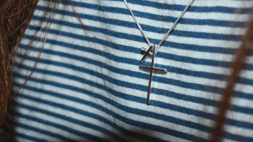 Two silver crosses around a persons neck.