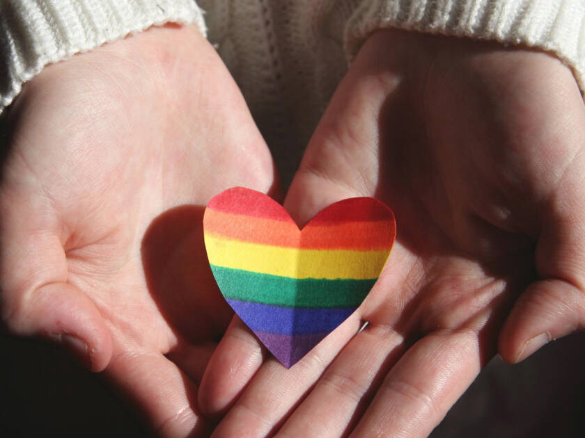 A rainbow heart in the hands of a person.
