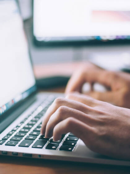 Hands typing on a laptop computer.