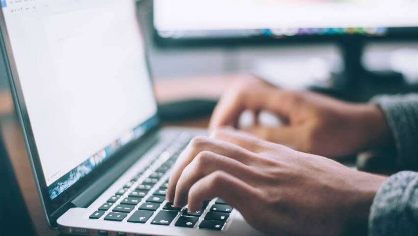 Hands typing on a laptop computer.