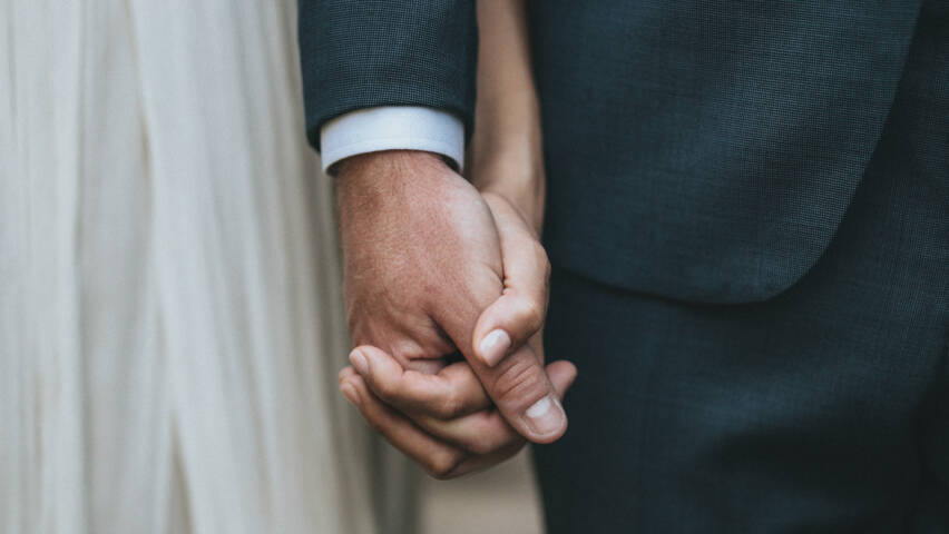 The bride and groom hand in hand.