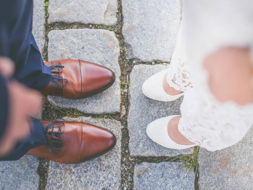 The feet of a bride and groom standing opposite each other.