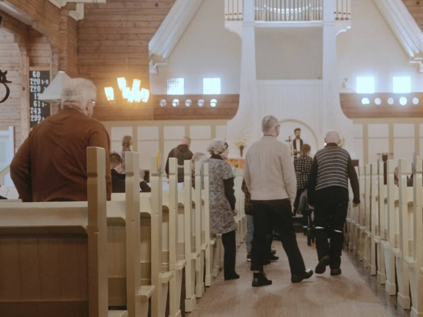 People walking in the aisle of a church.