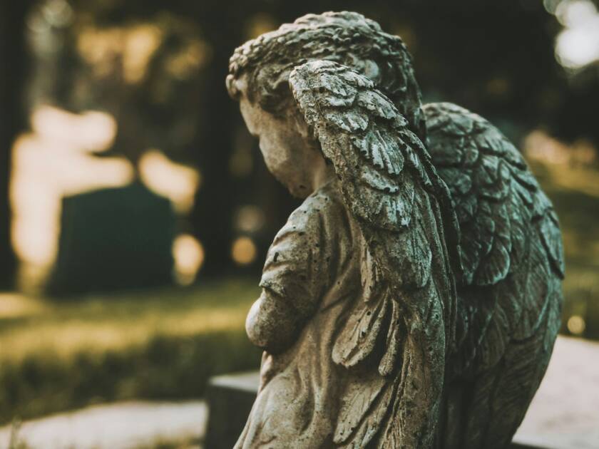 Statue of a small child with angel wings, on a graveyard.