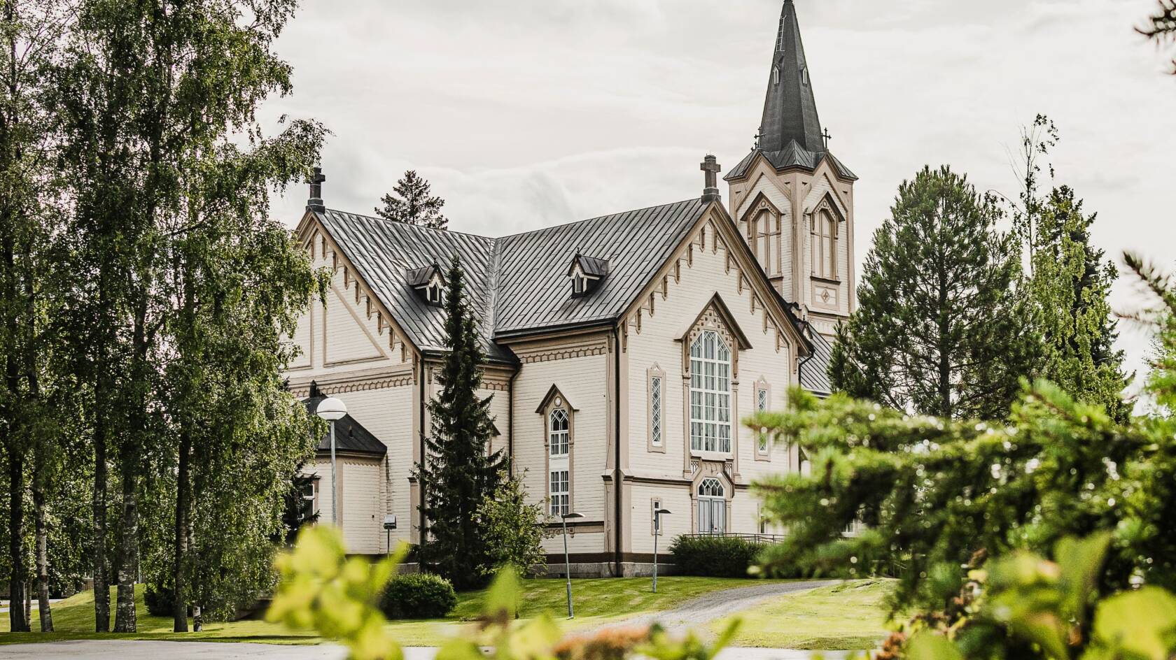 Vaalea kirkko koristeellisilla yksityiskohdilla. Puita ympärillä.