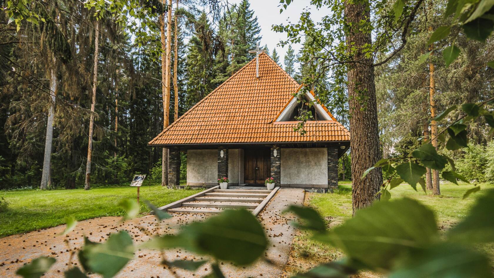 Punatiilikattoinen pieni kirkko puiden keskellä.