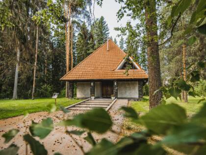 Small church with a red-tiled roof in the middle of the trees.