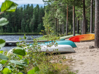 Metsäinen ranta, hiekalla veneitä pohja taivasta kohti.