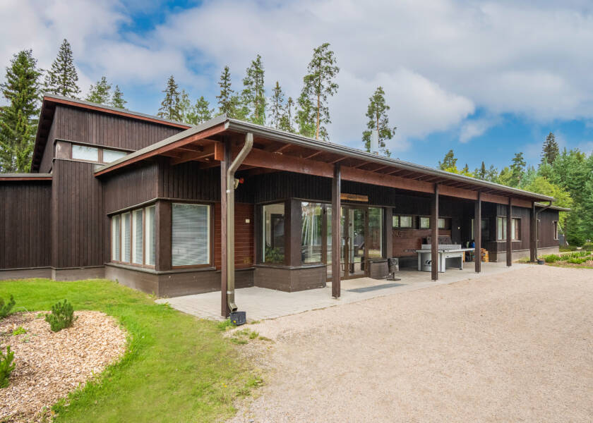 Tummanruskea puupaneloitu rakennus.
