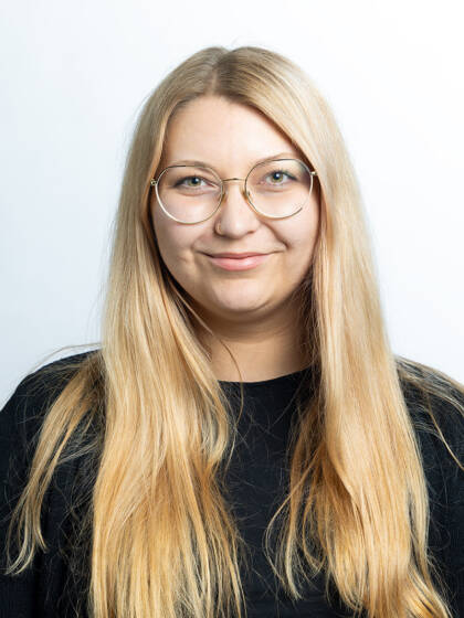 Henkilö, jolla musta paita, silmälasit ja vaaleat pitkät hiukset.