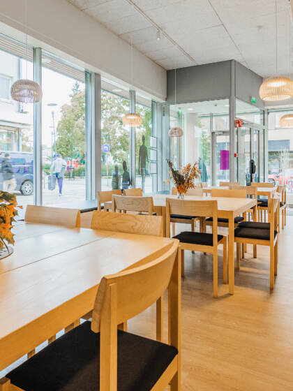Bright room with large windows facing the street. The room contains several table-and-chair sets.