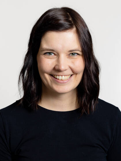Kasvokuva henkilöstä jolla on tumma olkapäille ulottuva tukka.