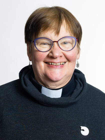 Kasvokuva henkilöstä jolla on ruskea tukka, silmälasit ja papinkaulus.