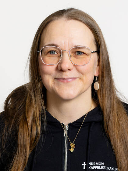 Kasvokuva henkilöstä jolla on pitkät ruskeat hiukset ja silmälasit.