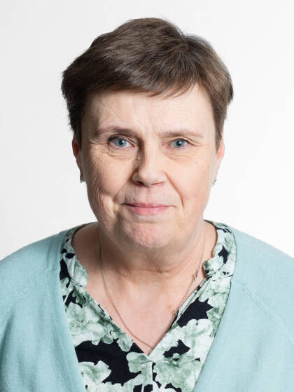 Henkilö jolla on lyhyet hiukset pienet korvakorut ja mintunvihreä paita.