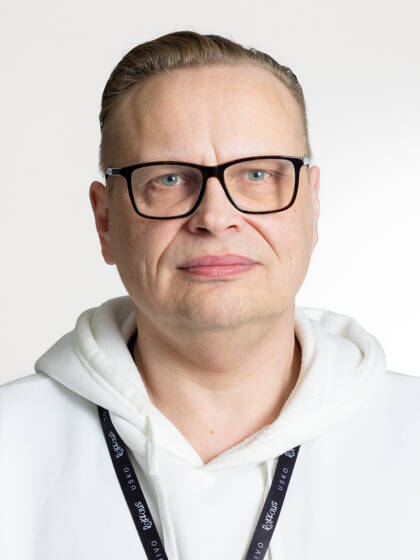 Henkilö jolla on lyhyet hiukset, silmälasit ja valkoinen huppari.