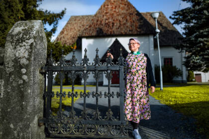 Henkilö seisoo Nurmon kirkon kirkkopihan portilla.