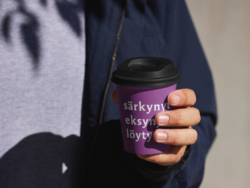 Henkilö pitää kädessään kahvimukia, jossa oleva teksti mainostaa seurakuntavaaleja.