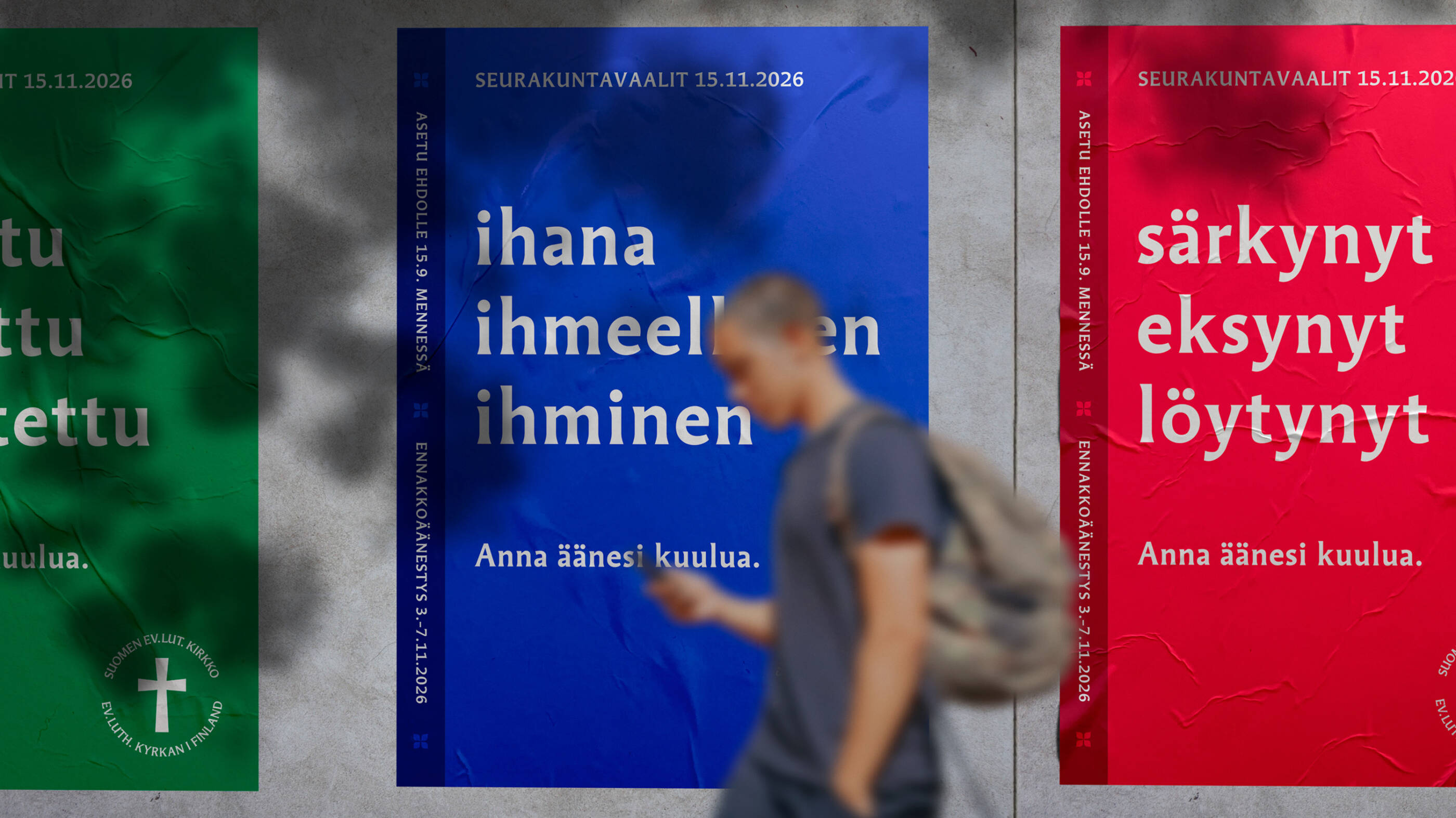 Henkilö kävelee seinällä olevien seurakuntavaalien mainosjulisteiden ohi.