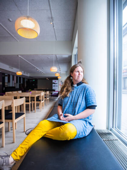 Henkilö istuu nuorisokahvila Kismuksen ikkunapenkillä ja katselee ulos.