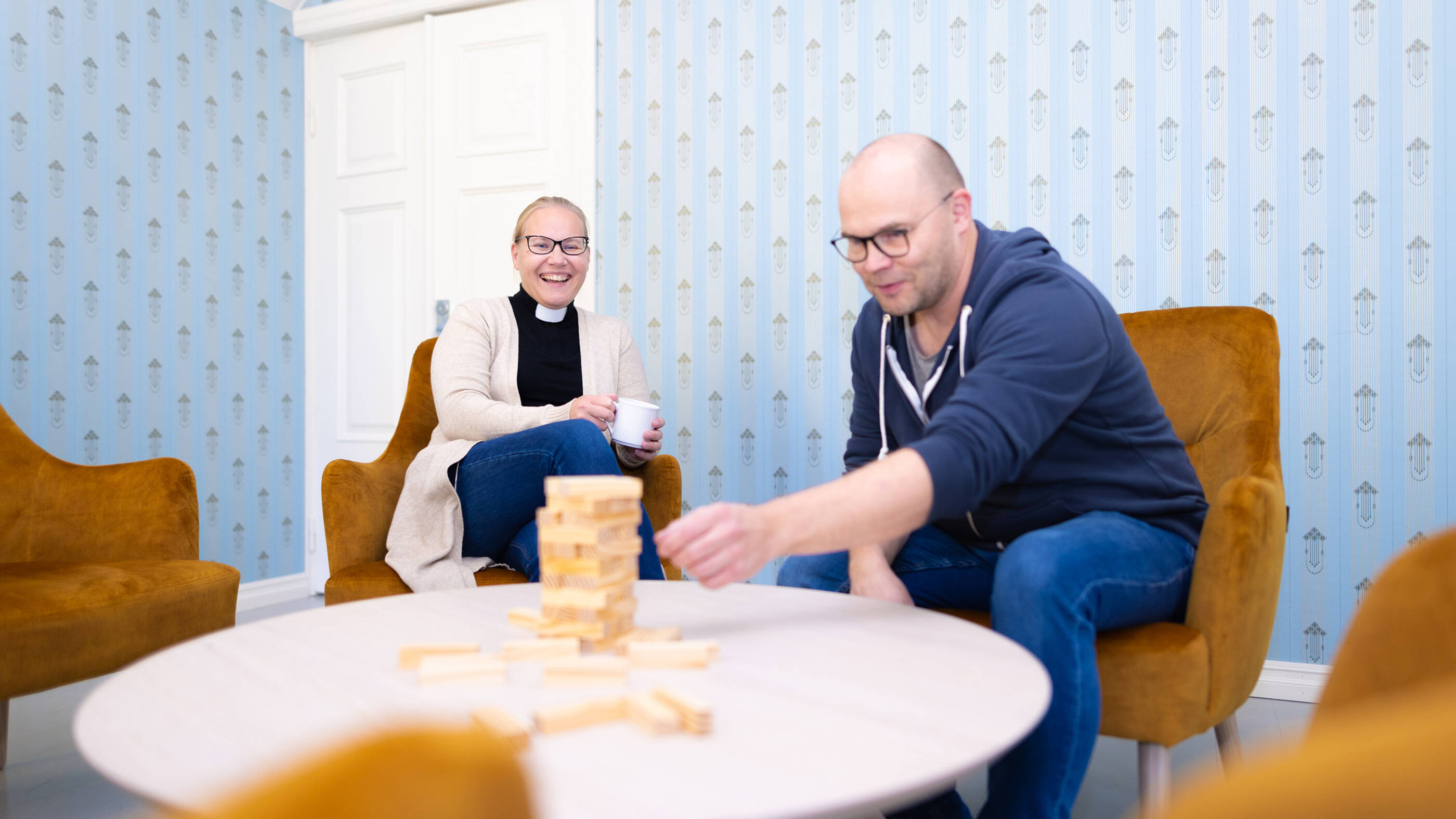 Kaksi henkilöä istuu pöydän ääressä pelaamassa seurapelejä.