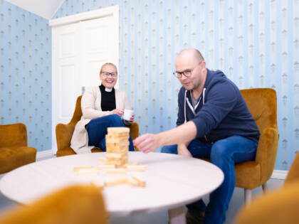 Kaksi henkilöä istuu pöydän ääressä pelaamassa seurapelejä.