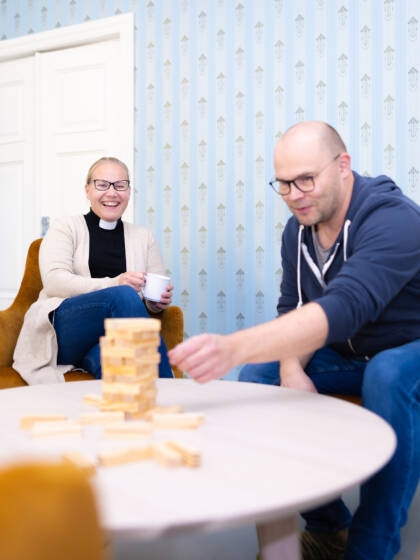 Kaksi henkilöä istuu pöydän ääressä pelaamassa seurapelejä.
