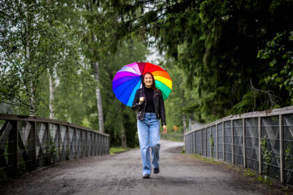 Henkilö kävelee sillalla sateenvarjon kanssa.