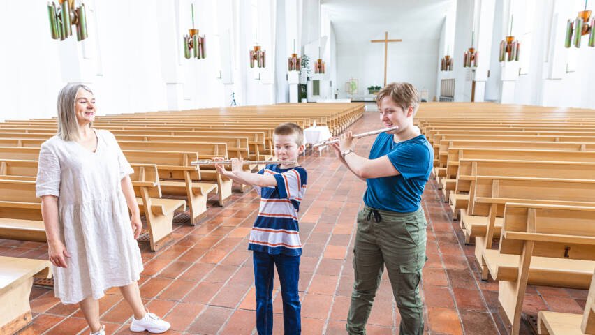 Yksi aikuinen ja kaksi lasta Lakeuden Ristin kirkkosalissa musisoimassa.