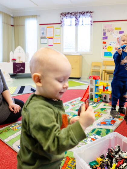 Aikuinen ja kolme lasta leikkivät yhdessä leluilla.