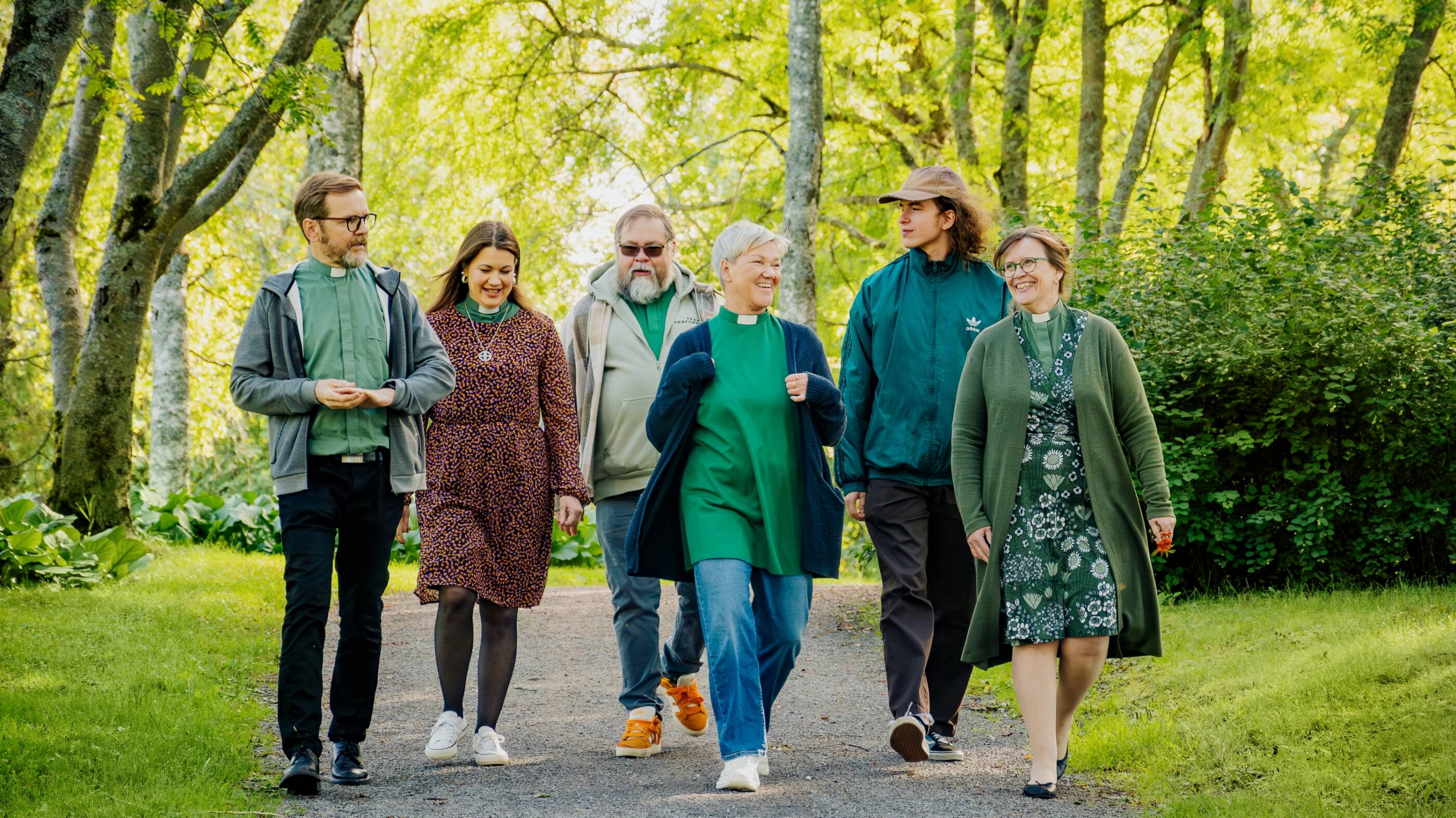 Kuusi seurakunnan työntekijää kävelee puistossa.