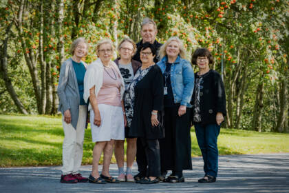 Seitsemän henkilöä puistossa, syksyinen maisema.