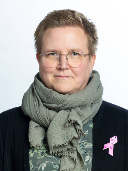 Ihminen vihreä kaulahuivikaulassa. Silmälasit.