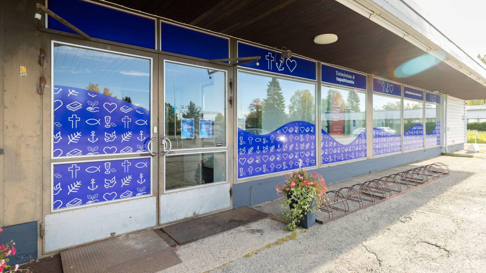 A brown building with extensive window surfaces featuring blue window graphics.