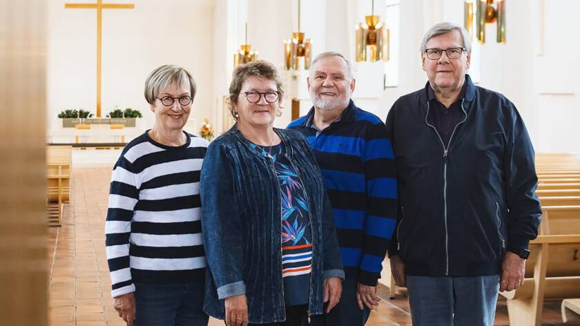 Neljä henkilöä Lakeuden Ristin kirkkosalin oviaukossa. Taustalla alttarin risti.