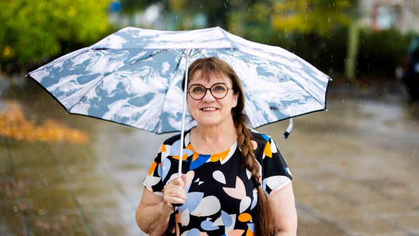 Ihminen ulkona sateenvarjo kädessä.