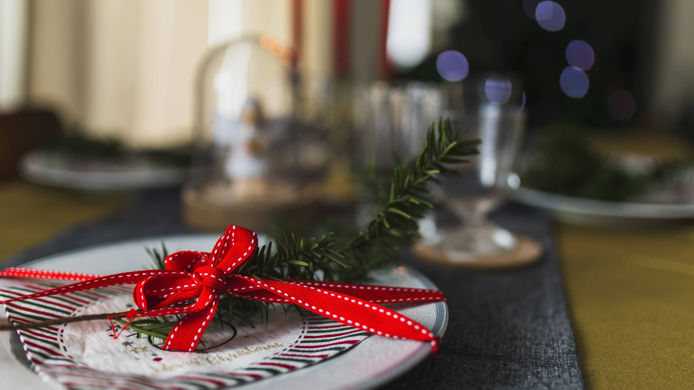 A plate with a spruce bough and a red bow on it.