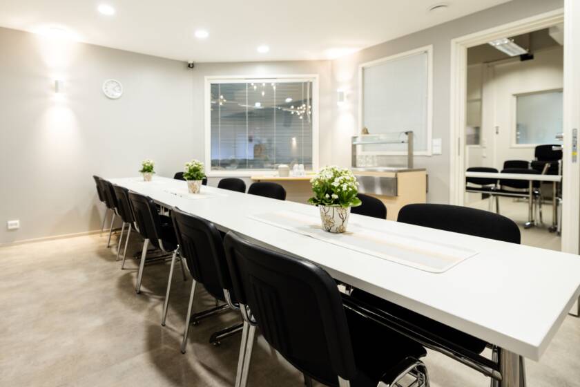 A meeting room with a white table and black chairs.